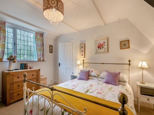 a bedroom with a bed and a chandelier at Little Crawfish Cottage in Thursford