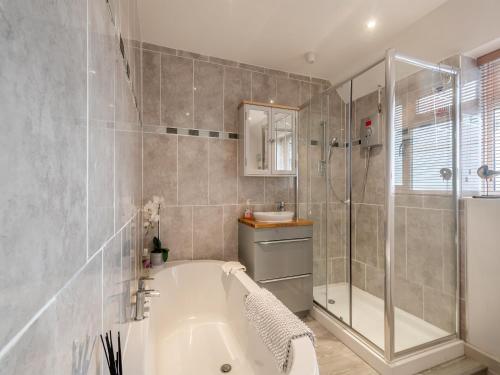 ein Bad mit einer Badewanne, einer Dusche und einem Waschbecken in der Unterkunft Little Crawfish Cottage in Thursford