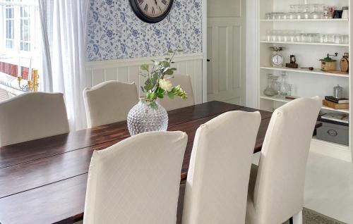 una mesa de comedor con sillas blancas y un jarrón con flores en 3 Bedroom Gorgeous Home In Sffle, en Säffle