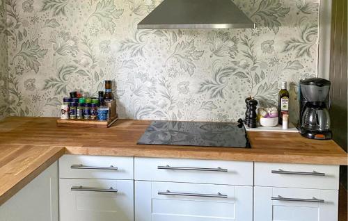 una cocina con armarios blancos y una pared con papel pintado floral en 3 Bedroom Gorgeous Home In Sffle, en Säffle