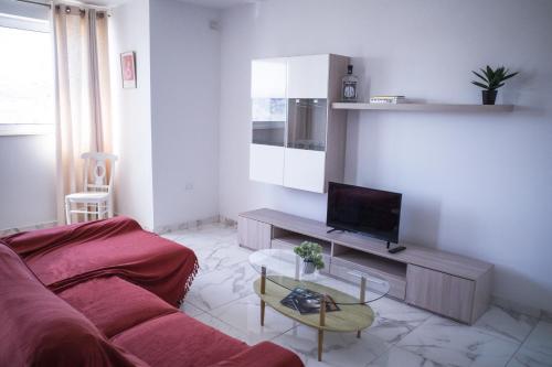 a living room with a red couch and a tv at Cova da Iria 5 in Tal-Pietà