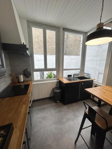 a kitchen with a sink and a table and windows at MAISON DE VILLE AVEC GARAGE ET TERRASSE in Lourdes