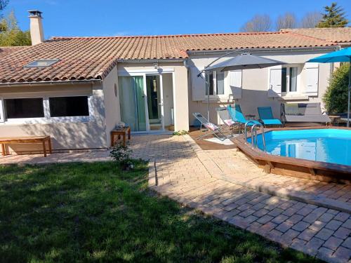 een huis met een zwembad en een parasol bij Villa Les oliviers in Le Pontet