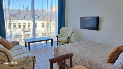ein Hotelzimmer mit einem Bett, einem Sofa und einem TV in der Unterkunft KaunasInn LA in Kaunas