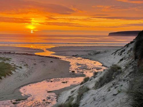 a sunset on a beach with the sun setting over the ocean at Caithness View Luxury Farm Lodges and BBQ Huts in Wick