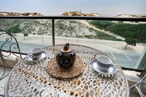a table with two cups and a vase on it at Azul Aprumado in Peniche de Cima