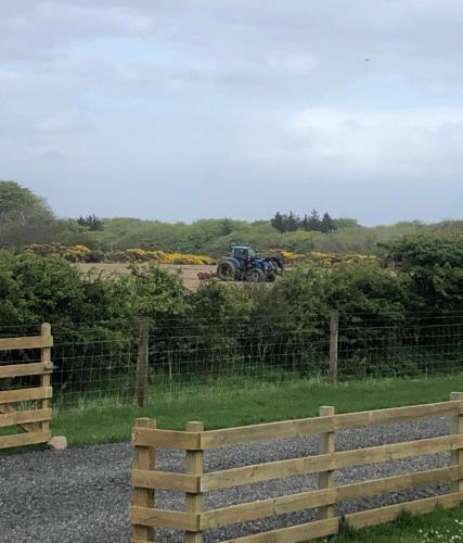 a tractor in a field behind a fence at Caithness View Luxury Farm Lodges and BBQ Huts in Wick