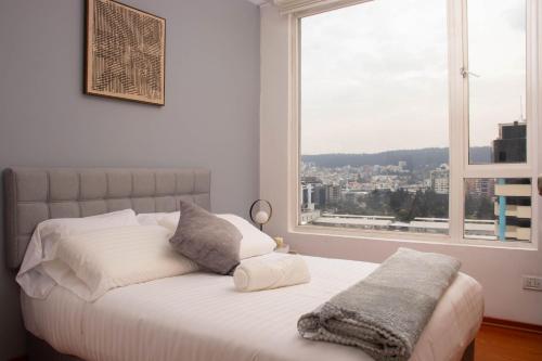 een slaapkamer met een wit bed en een groot raam bij 12 Floor Carolina Area best view 2br CCI Quito Coliving Ecuador in Quito