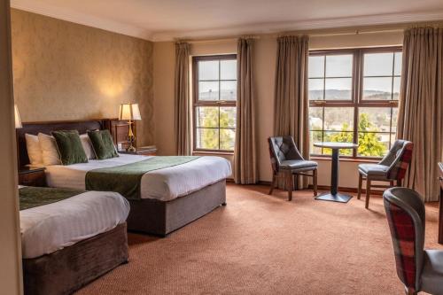 Cette chambre d'hôtel comprend deux lits, une table et des chaises. dans l'établissement Kee's Hotel, à Stranorlar