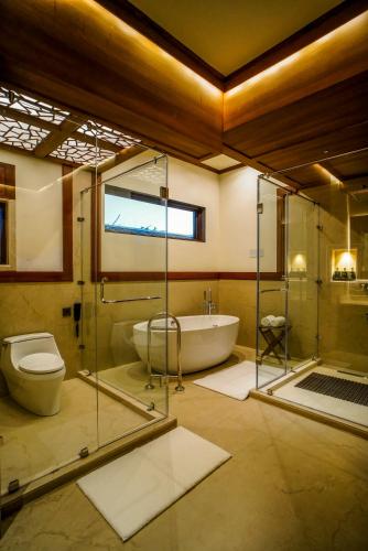 a bathroom with a glass shower and a toilet and a tub at Aahana Resort - Jim Corbett in Rāmnagar