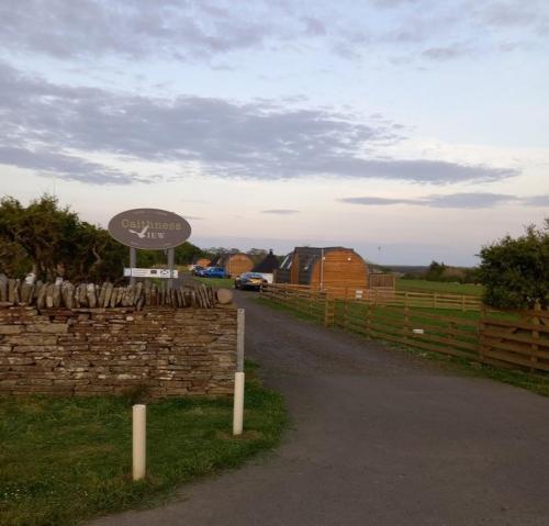 a sign on the side of a road next to a fence at Caithness View Luxury Farm Lodges and BBQ Huts in Wick