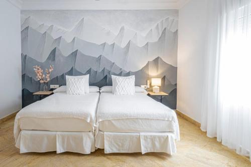 a bedroom with a large bed with a mountain mural on the wall at Labreña Hotel in Los Caños de Meca