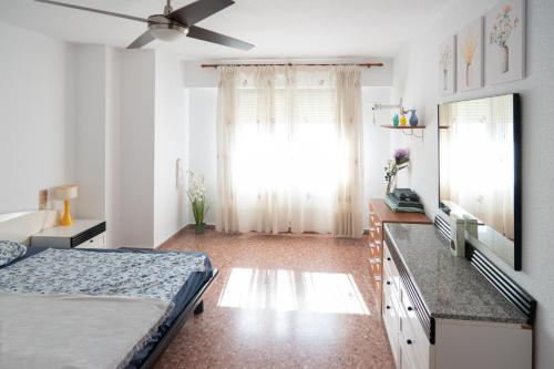 Schlafzimmer mit einem Bett, einem TV und einem Fenster in der Unterkunft An apartment in Xeraco with 3 bedrooms, located near beach and Gandia in Xeraco