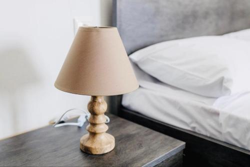 a lamp on a wooden table next to a bed at Aurora Syros Apartment in Ano Syros