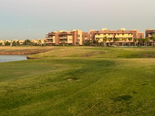 un parcours de golf avec un bâtiment en arrière-plan dans l'établissement Appartement 3 chambres en rez-de-jardin avec piscine Prestigia Marrakech, à Marrakech