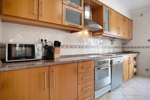 a kitchen with wooden cabinets and a microwave at Ferrel Casual Home - Baleal in Ferrel