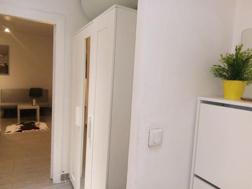 un couloir doté d'un mur blanc avec une plante. dans l'établissement Petit cocon en plein coeur de Paris, à Paris