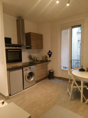une cuisine avec une machine à laver et une table dans l'établissement Petit cocon en plein coeur de Paris, à Paris