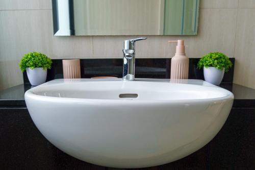 a white sink in a bathroom with two plants at Lovely Townhouse in Laguna Park in Thalang