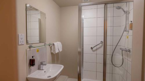 a white bathroom with a shower and a sink at The Tarbet Hotel in Tarbet