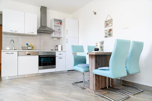 uma cozinha com cadeiras azuis e uma mesa de madeira em Apartman Murter 2+1 em Murter