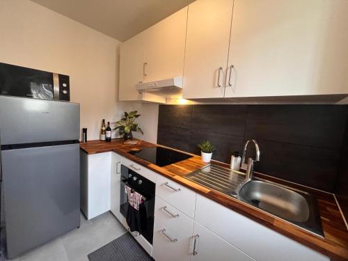 a kitchen with a sink and a refrigerator at Le Spacieux- Proche de Paris et Orly - Beau F2 de 52m2 en centre ville in Chilly-Mazarin