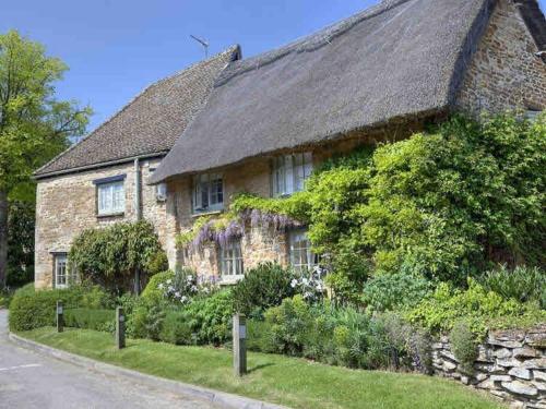 a large stone house with a grass roof at Cosy retreat in the heart of the Cotswolds. in Chipping Norton