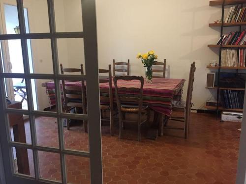 a dining room table with chairs and a vase of flowers on it at Agréable maison de ville avec parking gratuit in Montpellier