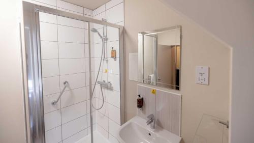 a white bathroom with a shower and a sink at The Tarbet Hotel in Tarbet