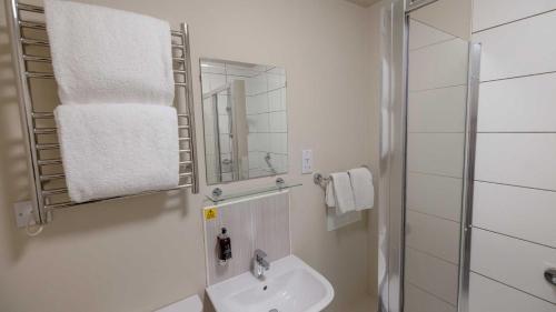 a white bathroom with a sink and a mirror at The Tarbet Hotel in Tarbet