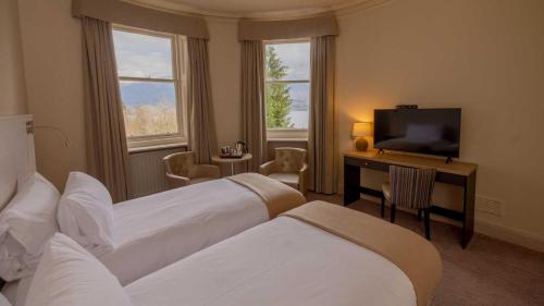 a hotel room with two beds and a television at The Tarbet Hotel in Tarbet