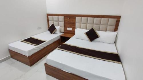 two beds in a room with white walls at HOTEL HIVIN AND PEANCE - TOP RATED AND SERCH PROPERTY AMRITSAR in Amritsar
