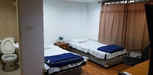 two beds in a room with a toilet and a sink at OM INN in Bangkok