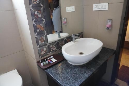 a bathroom with a white sink and a mirror at HSM Grand Inn, Chittoor in Chittoor
