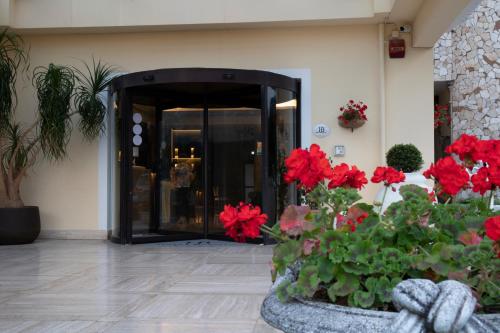 un vestíbulo con flores rojas frente a un edificio en Bel Sito Hotel Due Torri, en Manocalzati