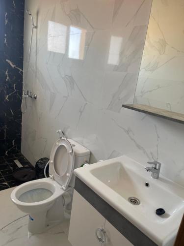 a white bathroom with a toilet and a sink at Nador Apartment in Nador