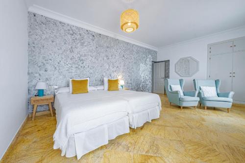 a bedroom with a large white bed and two blue chairs at Labreña Hotel in Los Caños de Meca