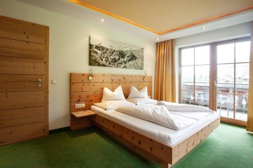 a bedroom with a large bed and a large window at Naturresort Senningerhof in Bramberg am Wildkogel