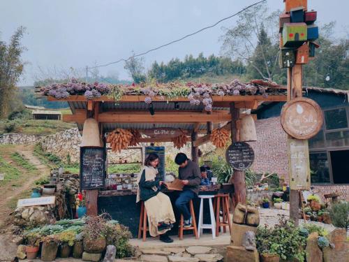 a man and woman sitting at a table in a flower shop at Sa Moc - La Maison House & Bungalow in Sa Pa