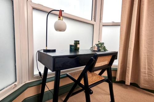 a black desk with a lamp and a chair in front of a window at Settle in Winchester - Stylish Self Check-In Rooms in Winchester