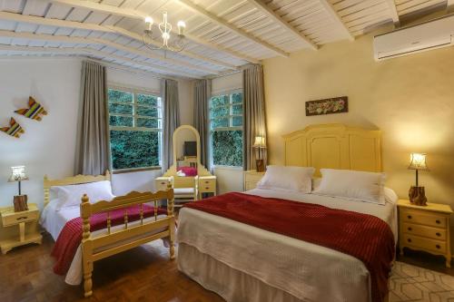 a bedroom with two beds and two windows at Pousada Famiglia Bartho in Espirito Santo Do Pinhal