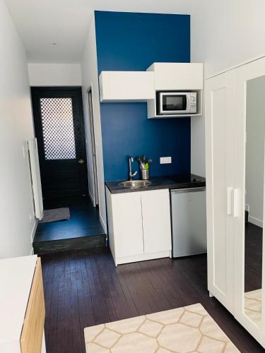 une cuisine avec des armoires blanches et un mur bleu dans l'établissement Studio cosy wifi terrasse CHU-Cite administrative-Primrose, à Bordeaux
