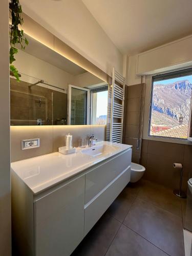 a bathroom with a sink and a toilet and a mirror at Buddy'S House Lake view Dog friendly whit garage in Abbadia Lariana