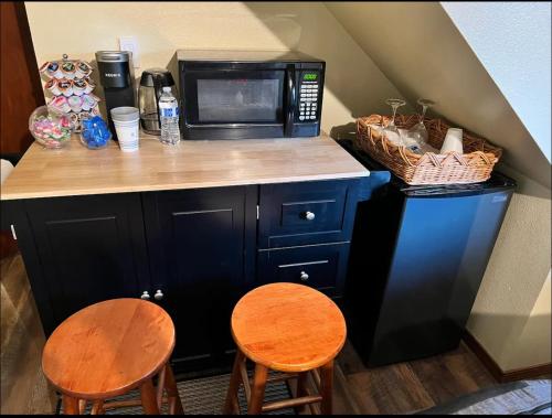 a kitchen with a counter with a microwave and two chairs at Private level of the house with SPA in Gresham