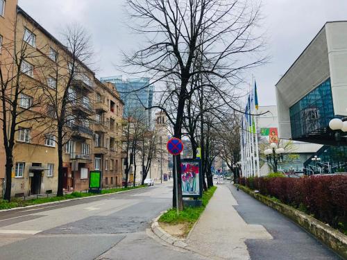 an empty city street with buildings and a blue sign at Centar City Sarajevo Apartman in Sarajevo