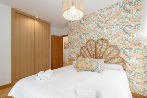 a bedroom with a white bed with a floral wall at Playa y descanso con parking by CABANA Rentals in Ribeira