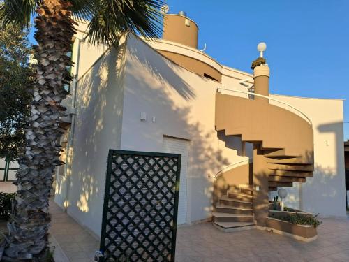 a white building with a staircase and a palm tree at VELA BIANCA in Punta Braccetto