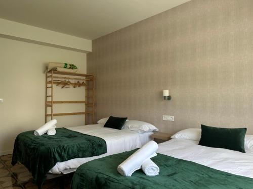 Cette chambre comprend 2 lits avec des draps verts et blancs. dans l'établissement Casa Grande do Costureiro Portomarín Camino de Santiago Francés, à Portomarín