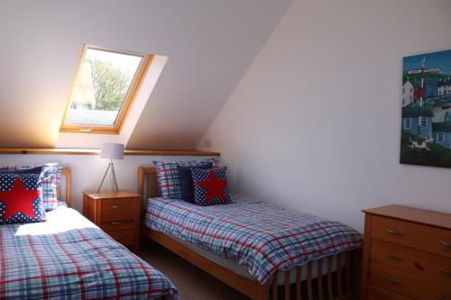 a attic bedroom with two beds and a window at Penlan Coastal Cottages in Aberporth