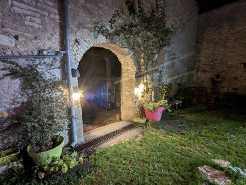 an archway in a stone building with potted plants at Le p'tit relai in Montbozon